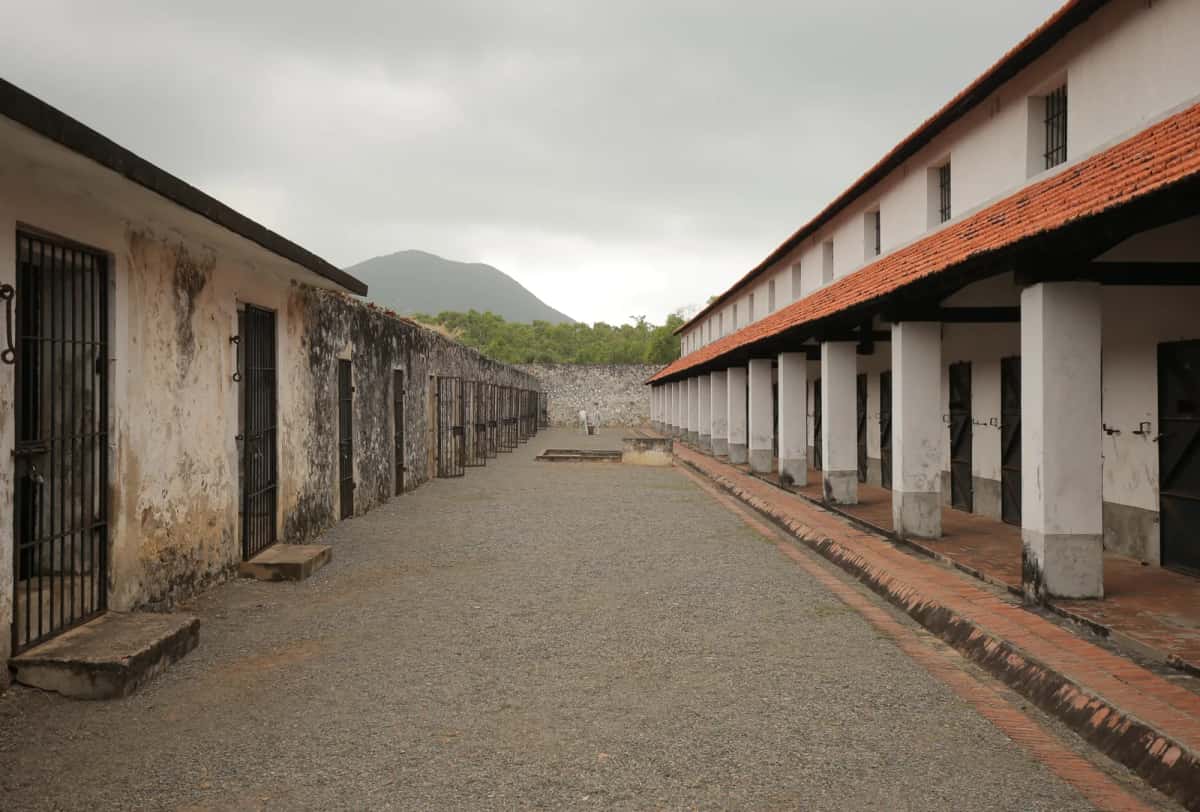 Cour gravillonnée entre deux bâtiments de cellules aux portes à barreaux, prison de Côn Đảo