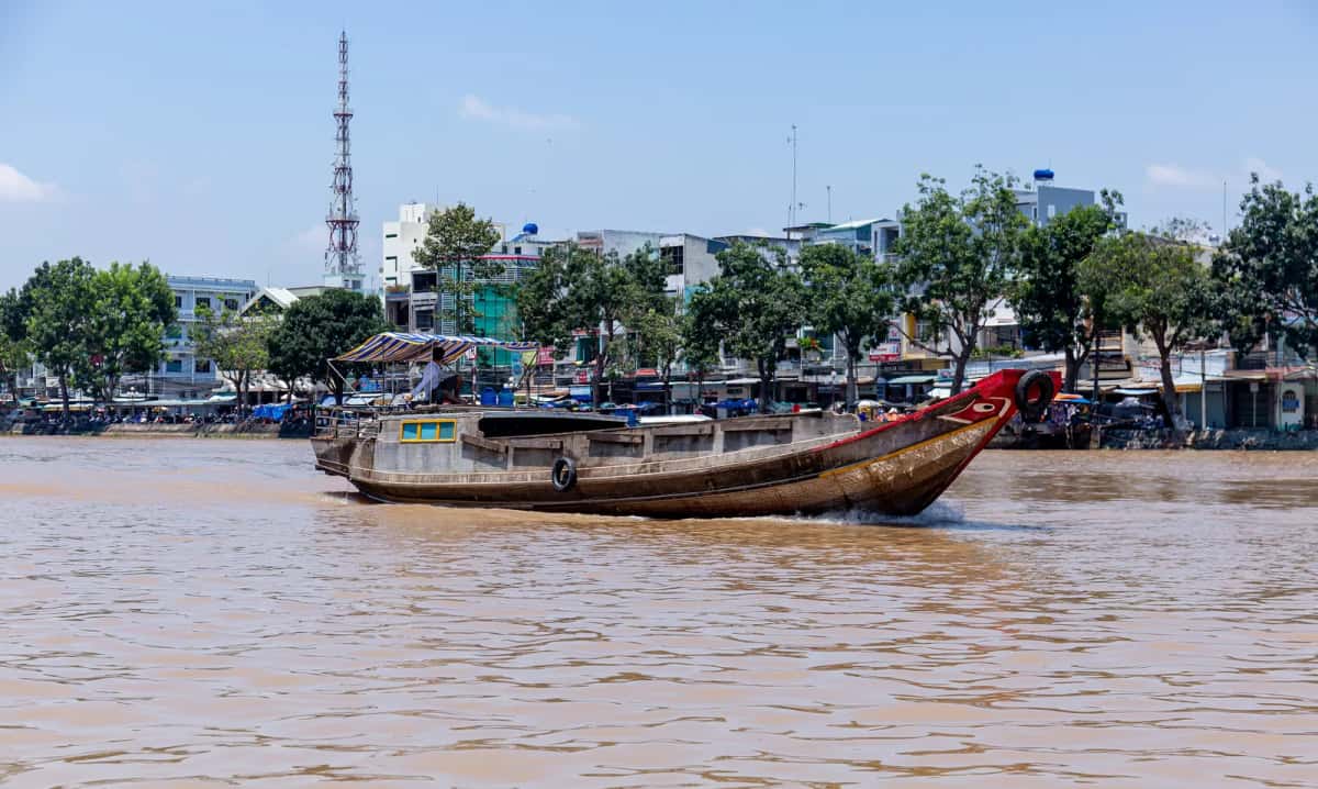 Bateau en bois à la proue rouge sur le Mékong devant le quai de Bến Tre