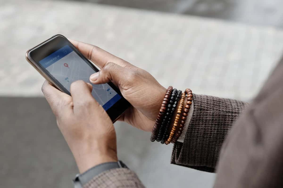 Mains tenant un smartphone affichant une carte de navigation GPS en voyage