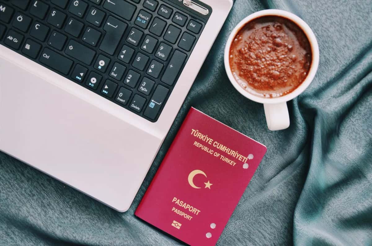 Passeport posé à côté d'un ordinateur portable, pour remplir une demande de visa en ligne