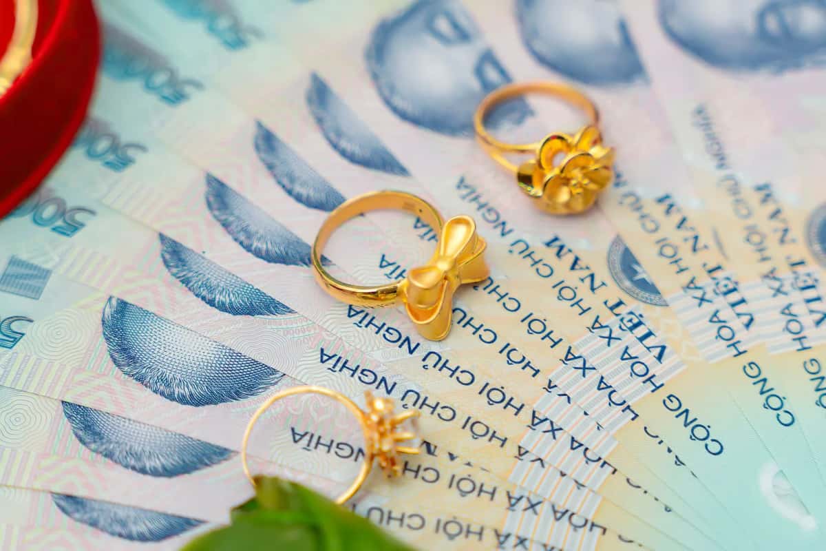 Billets de dongs vietnamiens en éventail avec des bagues en or posées dessus