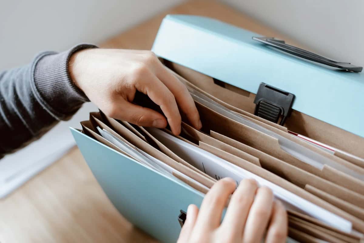 Mains feuilletant un classeur à soufflets rempli de documents administratifs
