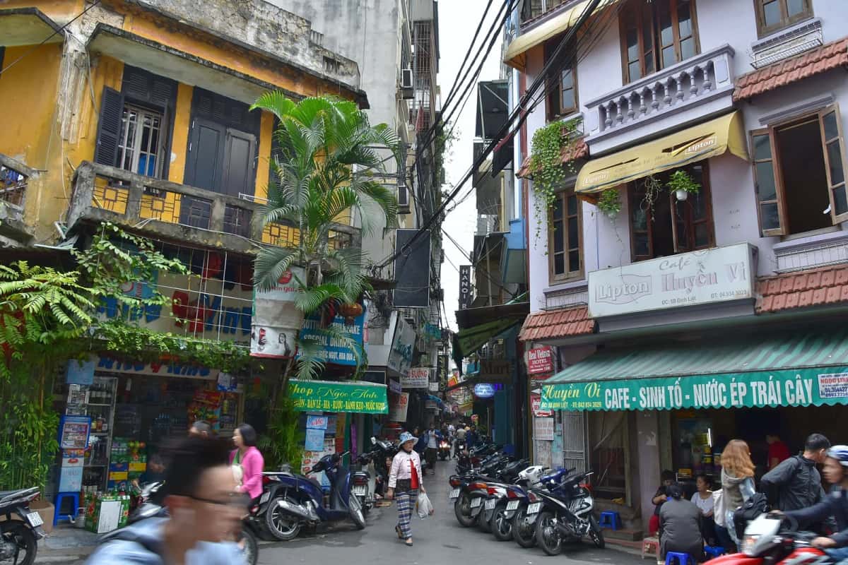 Ruelle du vieux quartier de Hanoï, maisons étroites, cafés et motos garées