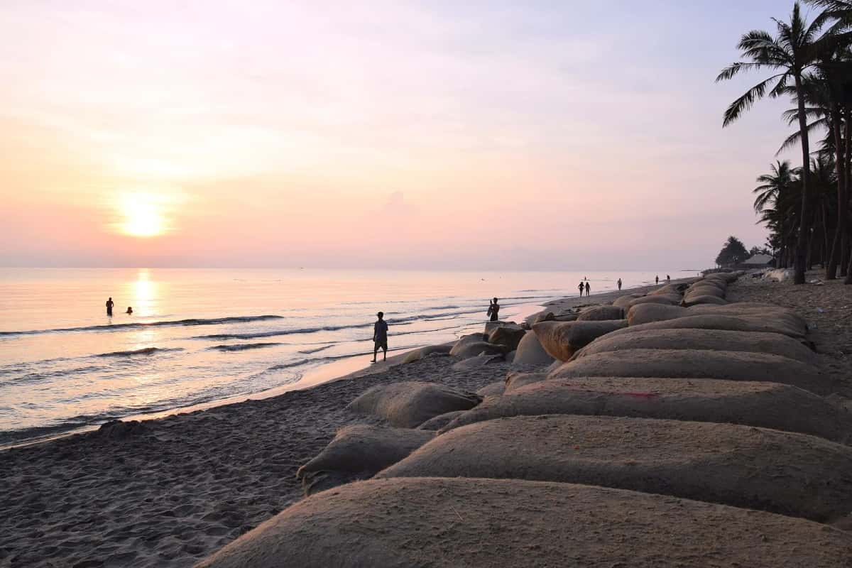 Lever de soleil sur une plage de Hội An, avec des sacs de sable posés sur le sable