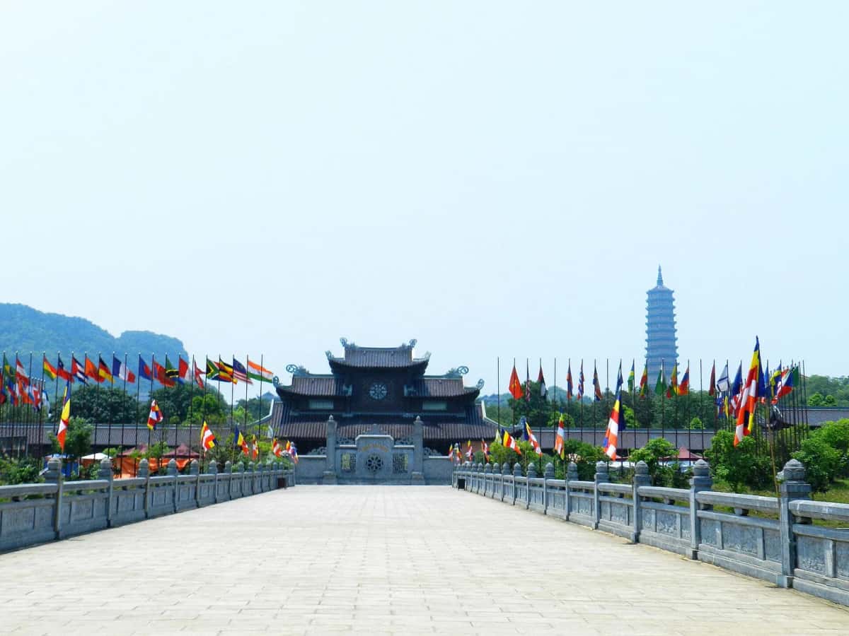 Allée d'entrée de la pagode de Bái Đính bordée de drapeaux, avec la grande tour en arrière-plan, Ninh Binh