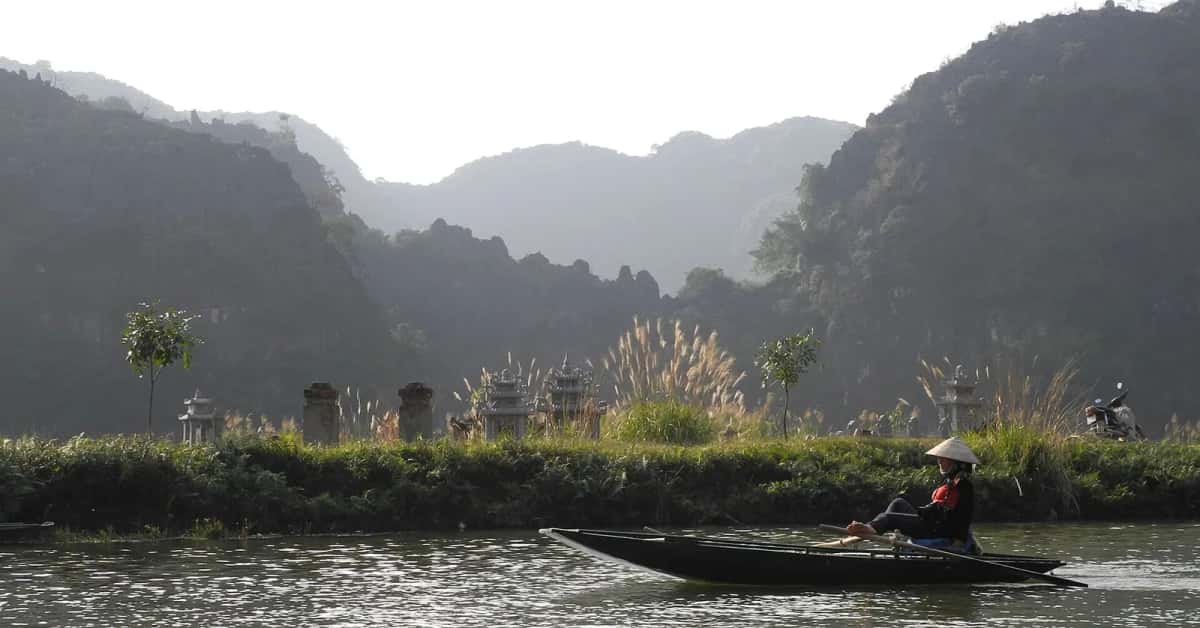 Rameuse en barque sur la rivière Ngô Đồng devant les falaises de Tam Cốc, Ninh Binh